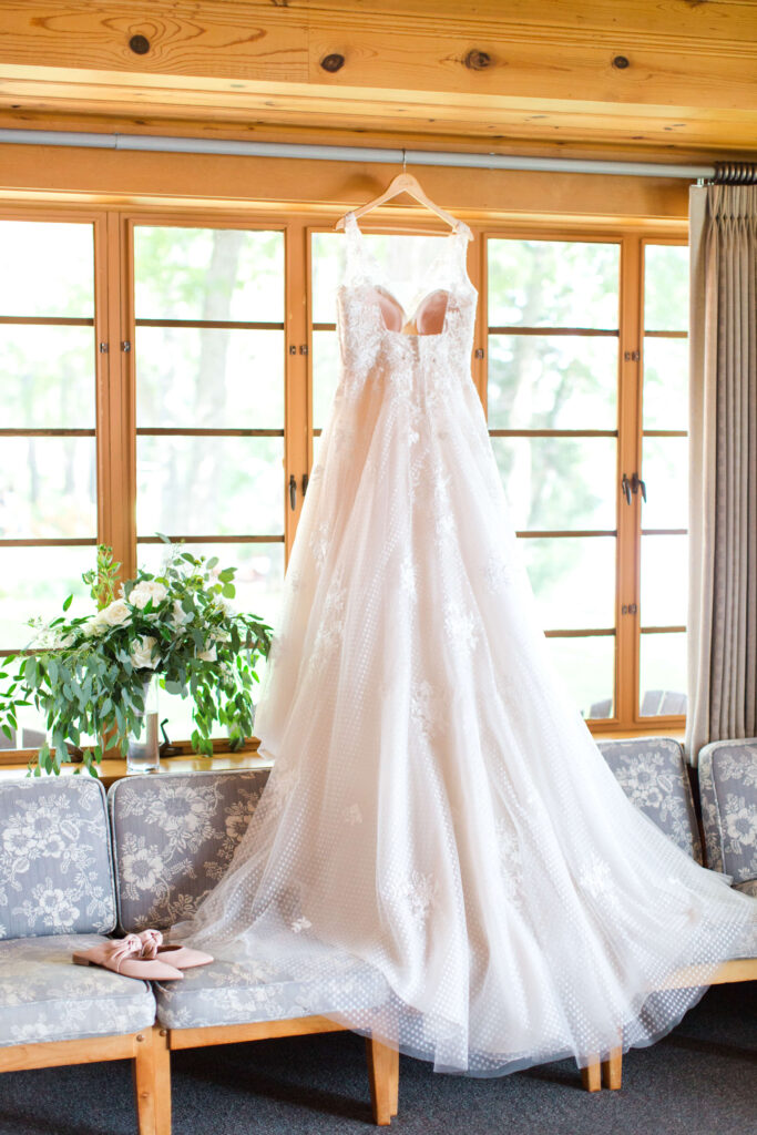 Dress hanging in front of lodge windows at elegant wedding at Red Crown Lodge