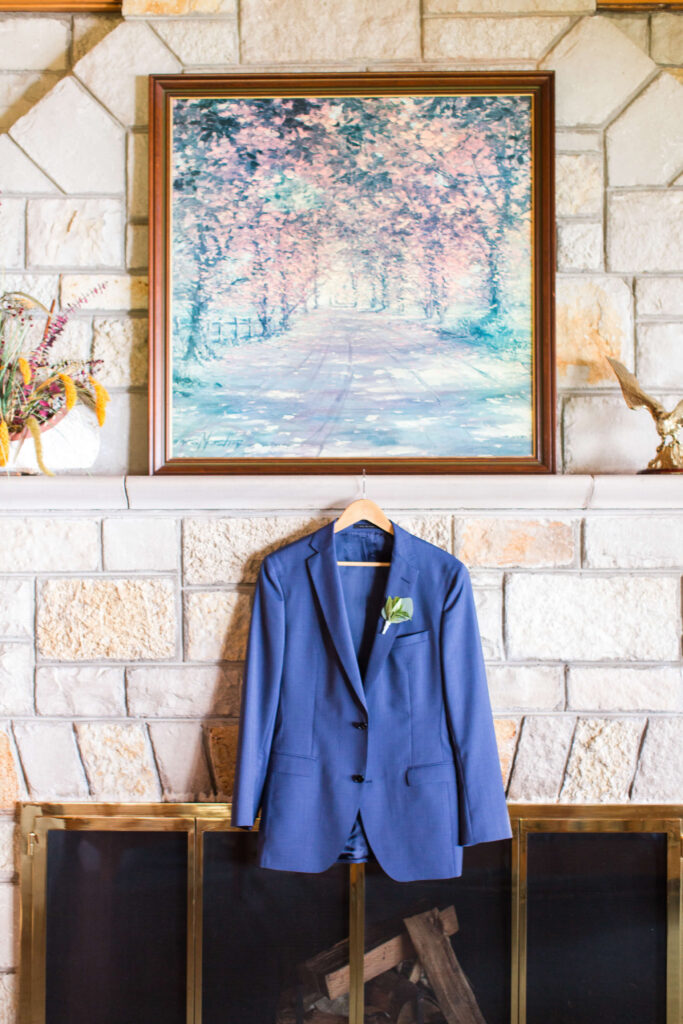 Grooms tux jacket displayed on fireplace mantle at elegant wedding at Red Crown Lodge