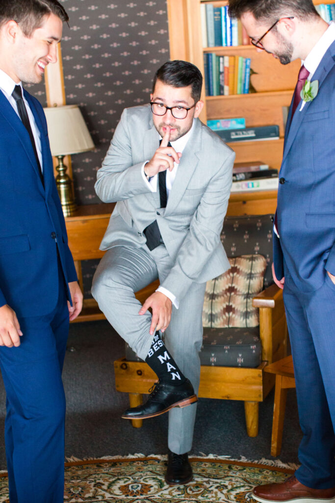 Best man showing off silly socks at elegant wedding at Red Crown Lodge