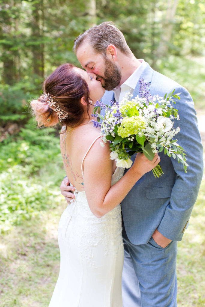 Bride & groom kiss in the woods at their Eagle River Cabin Wedding