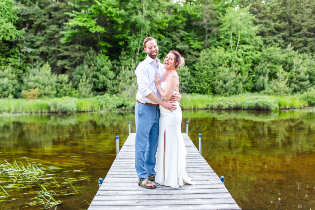 bride & groom share a laugh on the dock at their Eagle River Cabin Wedding