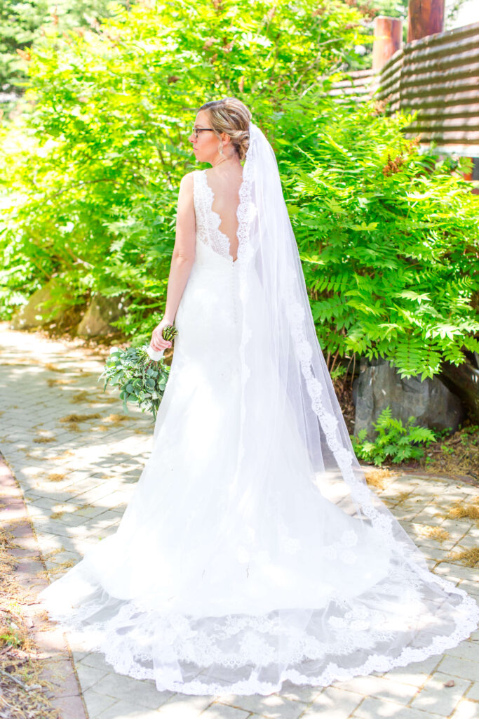 Bride in bridal gown with long veil posed on path outside of the main lodge at eagle waters resort