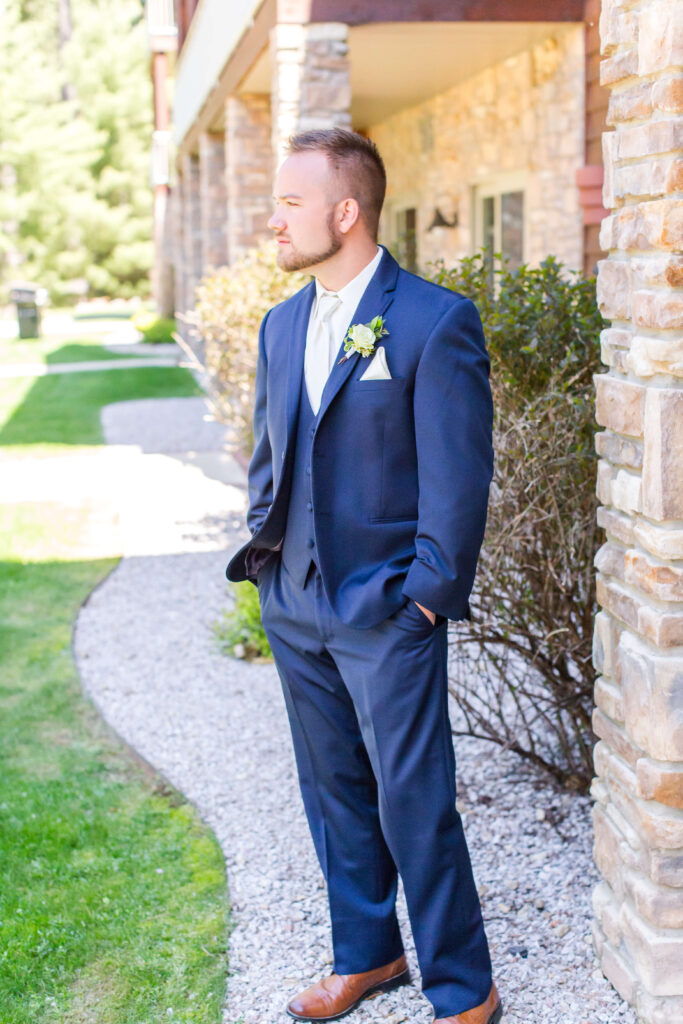 Groom posed outside of the main lodge at eagle waters resort, overlooking Eagle Lake