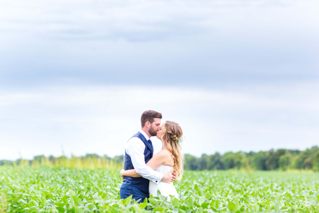 Bride & Groom kiss in field at summer wedding at farmin' betty's 