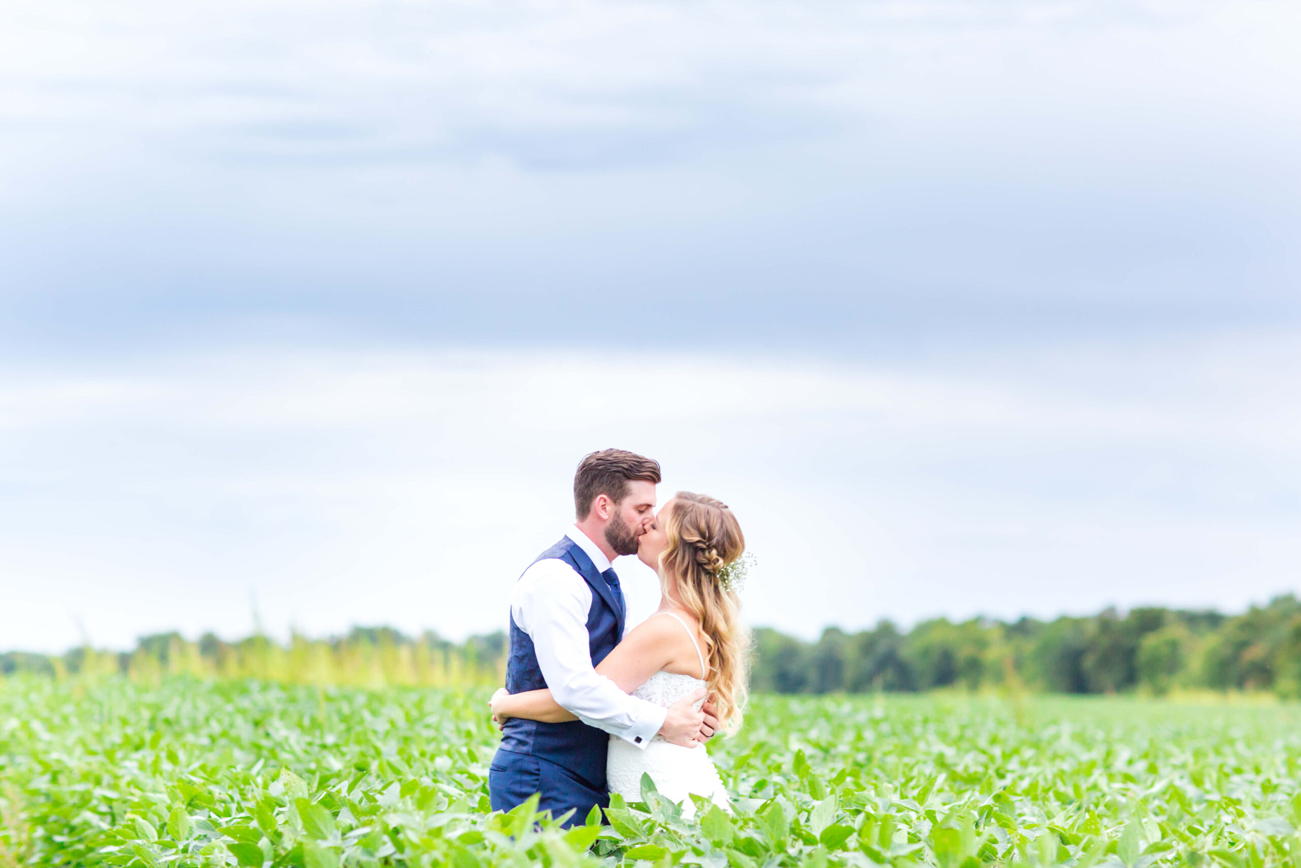 Bride and groom in green field with tall grass