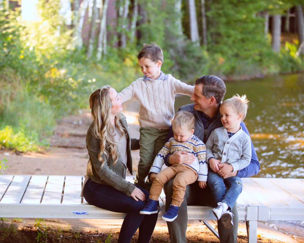 family of 5 sitting on dock together posing for photo. Minocqua Family Session Tips