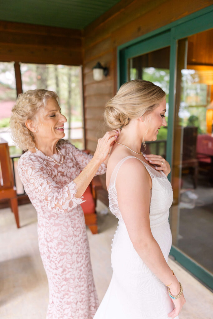 Mother of Bride helping bride with her necklace