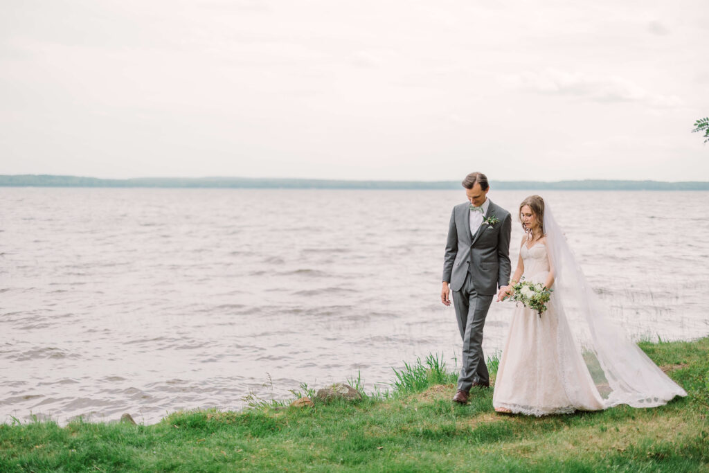 bride and groom walking along the shore of northern wi lake