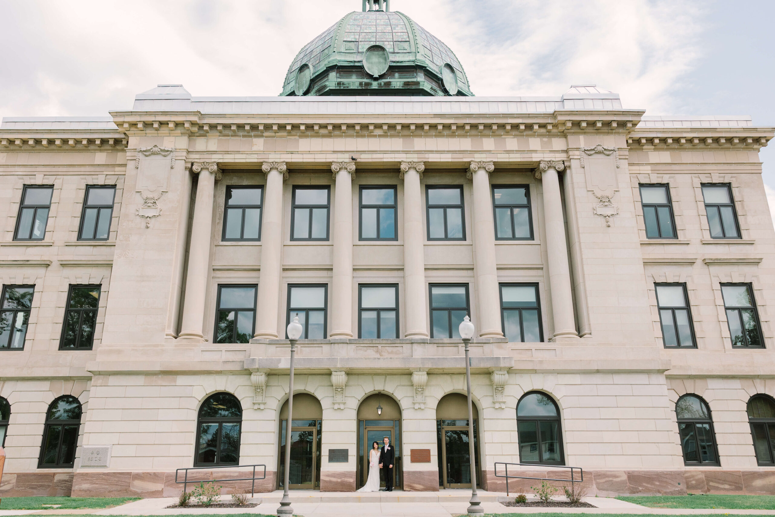 Bride and Groom posed in front of Oneida County Courthouse